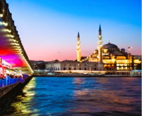 Side view of Istanbul’s skyline at sunset, with domes, minarets, and the Bosphorus glowing in soft light.